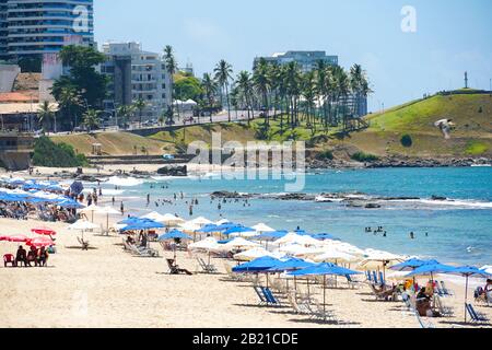 People enjoying sun, beach and blue water at Porto da Barra Beach next the Barra Lighthouse in Salvador Bahia Brazil. February, 22nd, 2019 Stock Photo