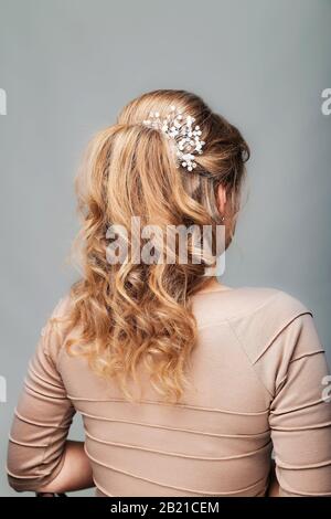 Wave curls hairstyle. Hairstyle on blond hair woman with long hair on a white background. Professional hairdressing services.Hair styling, making Stock Photo