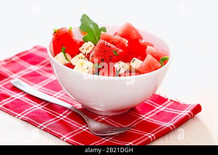 From above of square slices of watermelon cheese and greenery in ceramic bowl on towel with fork isolated on white background Stock Photo