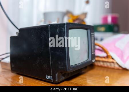 Closeup of one small black television retro vintage in dacha cottage home on wooden table in country countryside living room Stock Photo