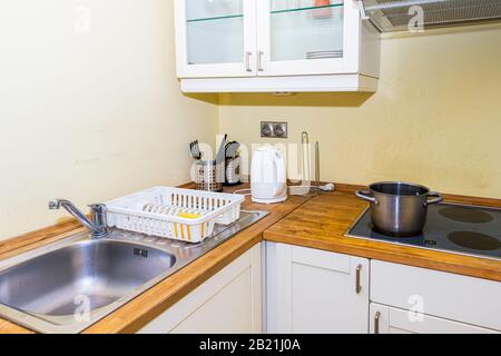 Rustic retro old fashioned kitchen with electric cook stove top stovetop cooktop with stainless steel pot and sink background in empty room Stock Photo