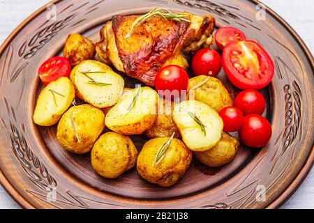 Roast chicken thighs and baby potatoes with soy sauce, maple syrup, fresh tomato cherry and spices. Concept of healthy autumn food baked in the oven. Stock Photo