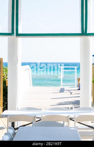 Seaside white wooden boardwalk and pavilion by ocean with water gazebo in Florida architecture view during sunny day steps to beach Stock Photo