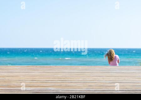 Seaside, Florida beach wooden boardwalk during sunny day in panhandle town village with ocean high angle steps and horizon with woman in background Stock Photo