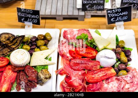 Salad display on plates with sun-dried tomatoes, olives and mozzarella cheese in famous Florence Italy Firenze Centrale Mercato with sign for expensiv Stock Photo