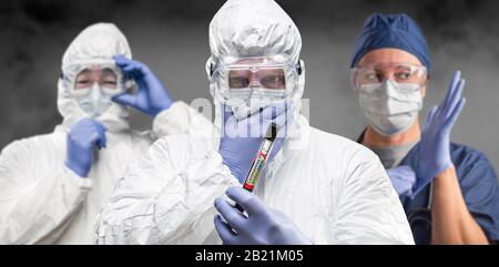 Team of Doctors or Nurses In Hazmat Gear Holding Positive Coronavirus Test Tube Banner. Stock Photo