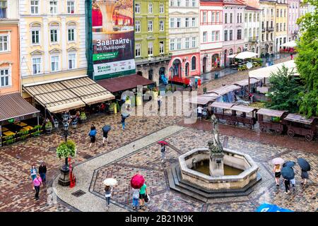 Lviv, Ukraine - July 31, 2018: Aerial high angle above view on Old town market square, people walking by Neptune fountain and restaurants in summer Stock Photo