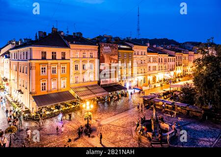Lviv, Ukraine - July 31, 2018: High angle above view on Old town market square, people by Neptune fountain and restaurants in summer night Stock Photo