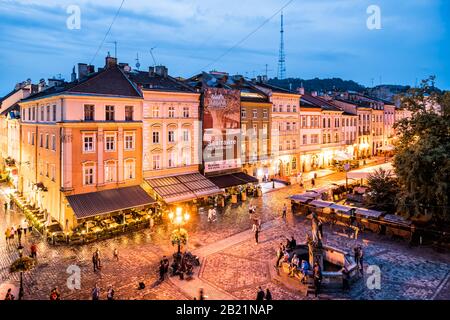 Lviv, Ukraine - July 31, 2018: Wide angle above view on Old town market square, people by Neptune fountain and restaurants in summer night Stock Photo