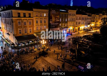 Lviv, Ukraine - July 31, 2018: Aerial above view of old town market square with people listening to music by Neptune water fountain street music perfo Stock Photo