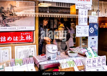 Uji, Japan - April 14, 2019: Traditional village with oldest store shop selling green tea free tasting sample with sign in english