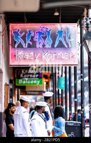 New Orleans, USA - April 23, 2018: Louisiana city with many people crowd sailors walking on Bourbon street with Krazy Korner neon sign Stock Photo