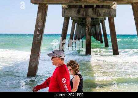 Fort Walton Beach, USA - April 24, 2018: People couple walking on beach under Okaloosa island fishing pier with ocean sea waves at Gulf of Mexico Stock Photo