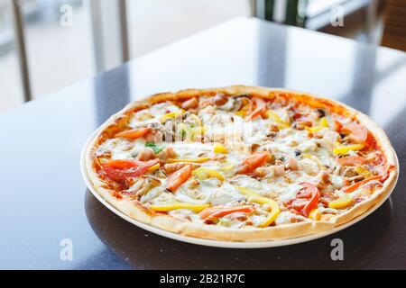 Delicious pizza with pepperoni and tomatoes dark table served in cafe or Italian restaurant. Hot pizza with mozzarella cheese. Stock Photo