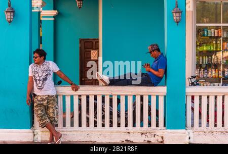 Coumel, Quintana Roo, Mexico - February 5, 2019: Two people relaxing leaning on the wall of a building in the centre of San Miguel. Stock Photo