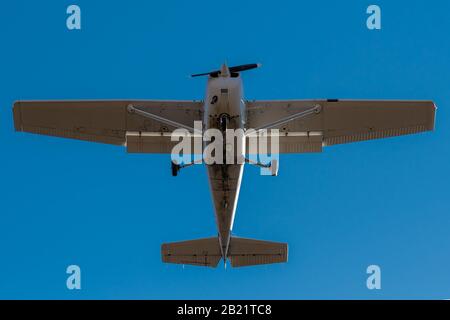 A small single engine airplane directly overhead. Blue sky above. Fast shutter to freeze propeller. Bottom of plane is dirty. Stock Photo