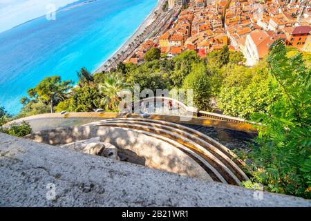 View looking down over the waterfall of Old Town, beach, promenade and hungry seagulls on Castle Hill, on the French Riviera in Nice, France. Stock Photo
