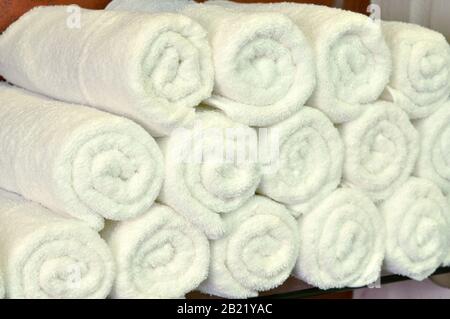 White towels texture background. White clean towels on bathroom shelf in spa salon or beauty salon. Many cotton white towels for washing hair and Stock Photo