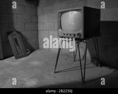 A black and white photo of an old TV from the 1950s forgotten and abandoned in a basement. Stock Photo