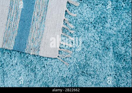 blue fluffy floor covering with soft high pile and a gray cotton napkin with pompons on it Stock Photo