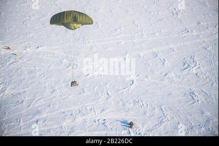 A pallet of cargo parachutes its way down out of an Alaska Air National Guard C-17A assigned to the 144th Airlift Squadron, during a rescue resupply mission at Deadhorse, Alaska, in support of Exercise Arctic Eagle 2020, Feb. 26, 2020. The Alaska National Guard is hosting Exercise Arctic Eagle 2020, a joint-training exercise, Feb. 20 – March 6, 2020 throughout Alaska, including Joint Base Elmendorf-Richardson, Eielson Air Force Base, Fort Wainwright, the Yukon-Kuskokwim Delta, and as far north as Teshekpuk Lake. As a homeland security and emergency response exercise, AE20 is designed to increa Stock Photo