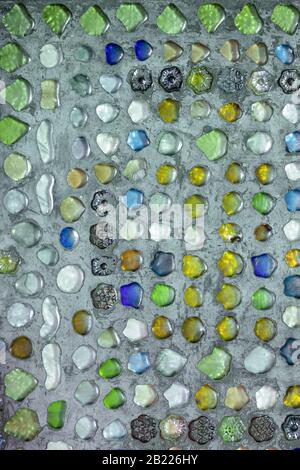 Colored glass pieces are glued on the concrete surface. A decorative pattern has been created. Stock Photo