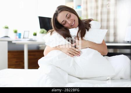 Girl sitting on bed hugging pillow and blanket Stock Photo