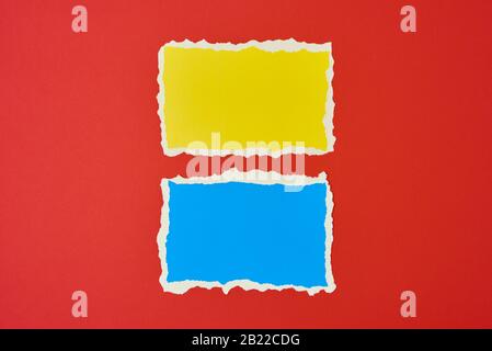 Two ripped paper torn edge sheets on red background. Template with piece of color paper Stock Photo