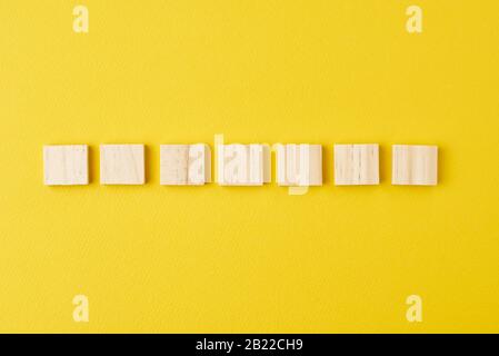 Wooden blocks in row on yellow background, top view Stock Photo
