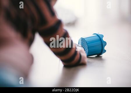 Baby boy playing with plastic cylinder on a hardwood floor Stock Photo