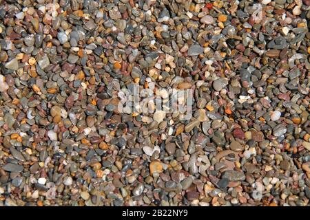 A Background of Wet Seaside Beach Gravel Stones. Stock Photo