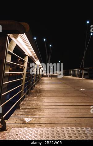 Hidden lights on the metal railings a bridge with a floor of wooden boards and several lights. Stock Photo