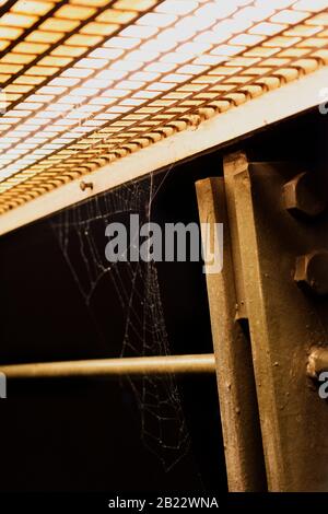 A spider web on metal railings awaits the built-in light Stock Photo