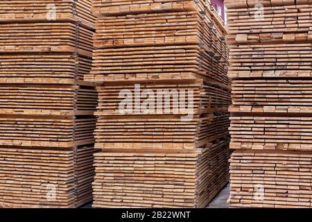 Large stacks of wooden planks full frame background with perspective. Woodwork industrial storage. Stock Photo