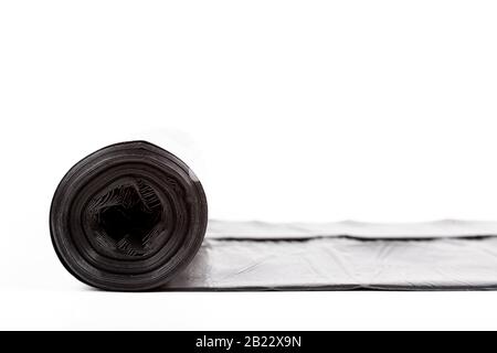 Single rolled out thick black roll of garbage bag isolated on white. Trash bag rolled out, generic home use household items, garbage disposal, plastic Stock Photo