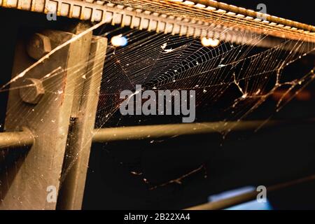 A spider web on metal railings awaits the built-in light. Stock Photo