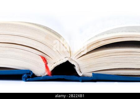 Simple opened empty light blue thick book with red tab, white background, macro, closeup, text blurred. Reading, writing, gathering knowledge Stock Photo