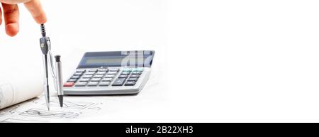 Wide banner, human hand, finger pressing down on top of a rotating compass, business calculator in the background, copy space on the right Stock Photo