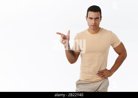 Mad, disappointed masculine man deal with personal mistakes, pointing finger left at empty white space, frowning upset and disagree, looking angry Stock Photo