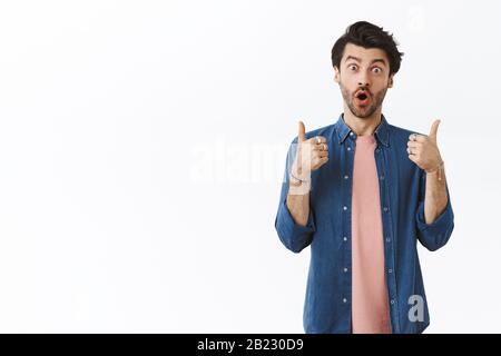 Surprised and impressed handsome man leaving positive feedback as trying new product at favorite cafe, showing thumbs-up saying all awesome, folding Stock Photo