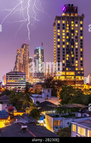 After the hot and humid heat of the day, at dusk lightning flashes over the skyline of Colombo, the capital city of Sri Lanka, lights up at dusk. Colo Stock Photo
