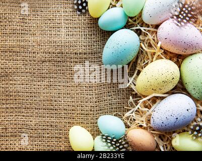 Easter eggs on a sackcloth and straw . Happy Easter  multicolored  easter eggs. Background with easter eggs. Flat lay, top view. Stock Photo