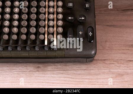 Part of the old counting mechanism, dusty vintage arithmometer standing on a wooden board Stock Photo