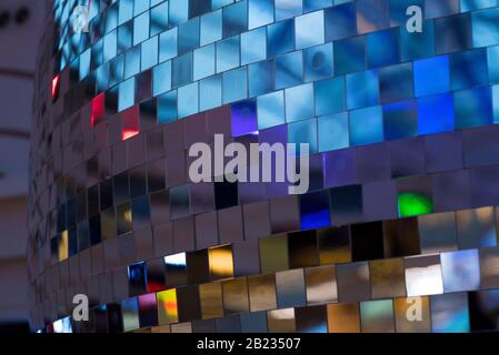 Colorful square metallic tiles on a wall or floor. Blue, green, teal, yellow, orange, purple reflective tile pattern. Shiny tile pattern with purple, Stock Photo