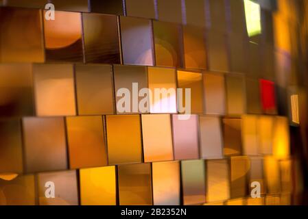 Colorful square metallic tiles on a wall or floor. Blue, green, teal, yellow, orange, purple reflective tile pattern. Shiny tile pattern with purple, Stock Photo