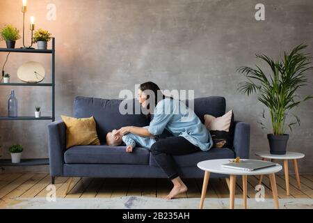 Young Mother Playing with Children on the Couch. happy family. home comfort. Stock Photo