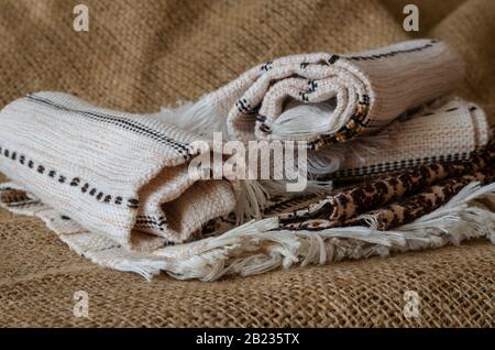 Set of linen towels on burlap background. Twisted Light Towels. Side view. Eye level shooting. Close-up. Selective focus. Stock Photo