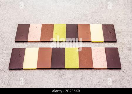 Assorted chocolate with different cocoa content. Sweet dessert abstract composition. On a stone concrete background, flat lay Stock Photo