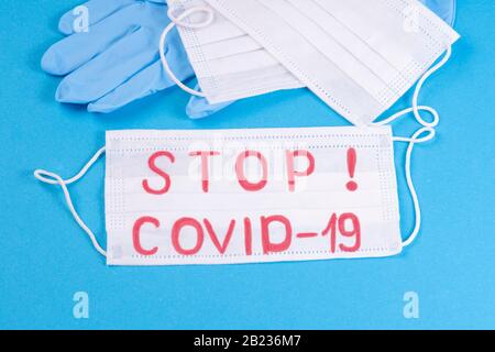 Respirator mask a mandatory personal protective equipment.Covid-19,coronovirusBlue medical gloves on a blue background with a white medical mask with Stock Photo