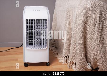 portable air cooler and humidifier on casters in domestic living room to improve indoor clmate Stock Photo
